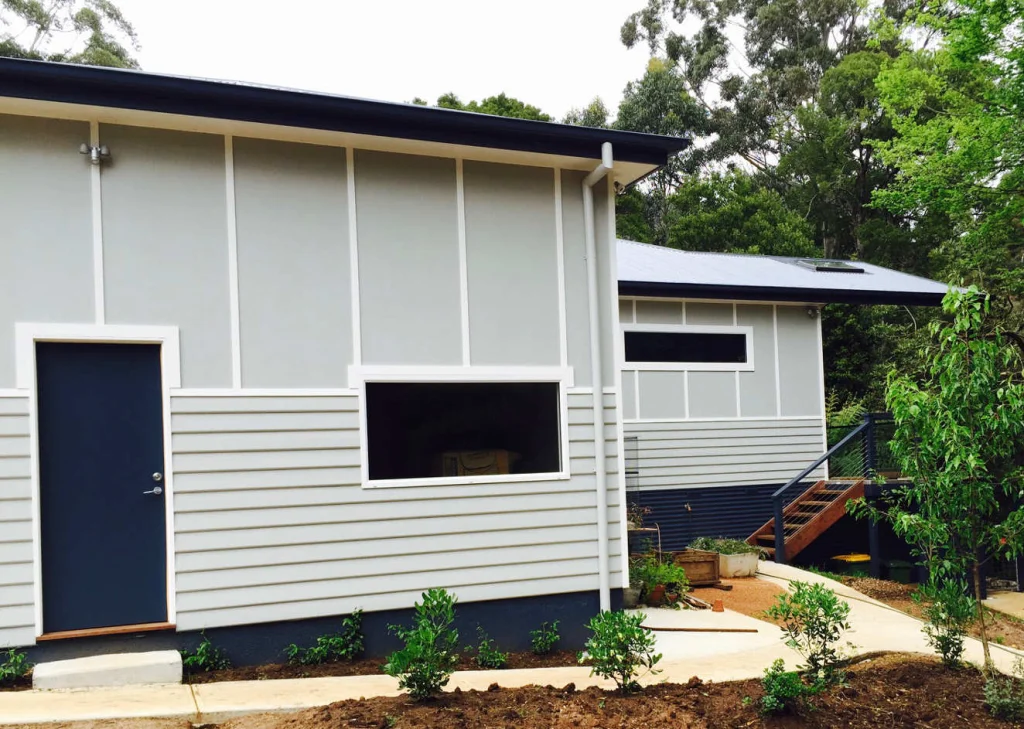 Light grey weatherboard home with a navy front door