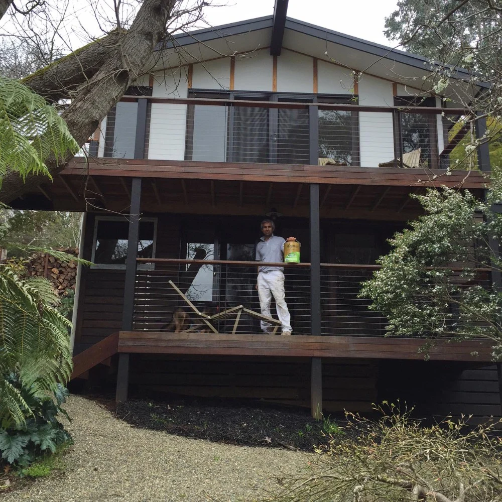 Painter working on the balcony of a two-storey timber home
