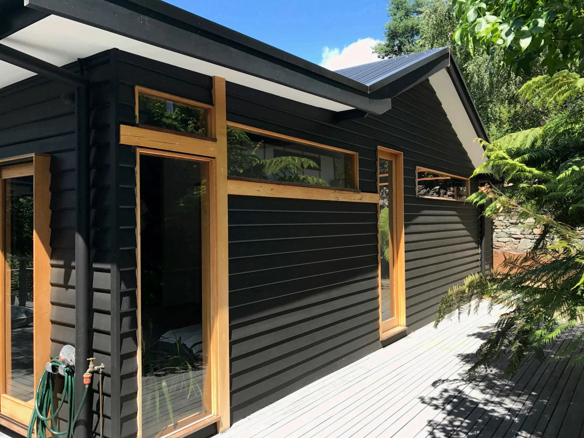 Charcoal weatherboard home with natural timber window frames