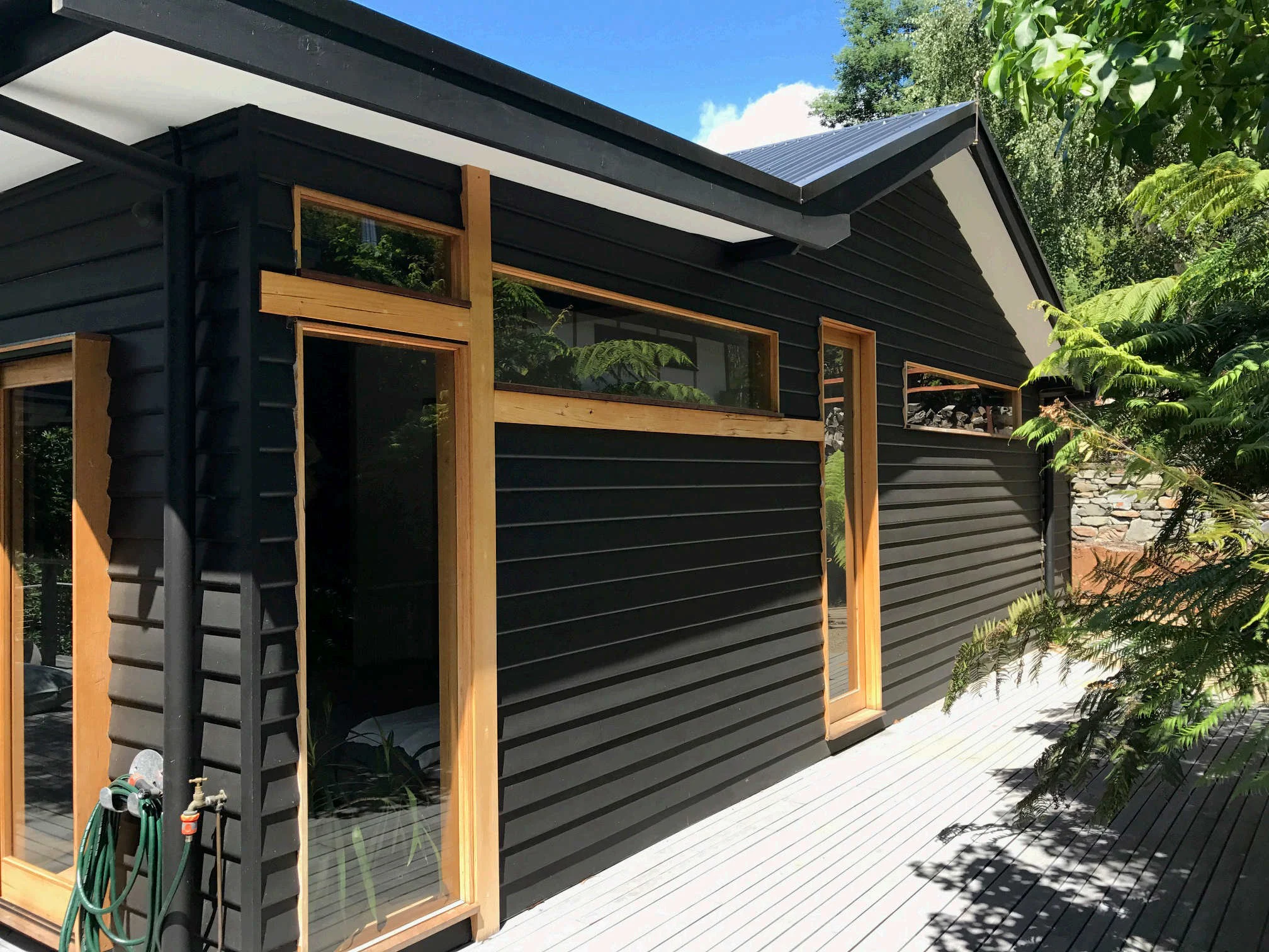 Charcoal weatherboard home with natural timber window frames