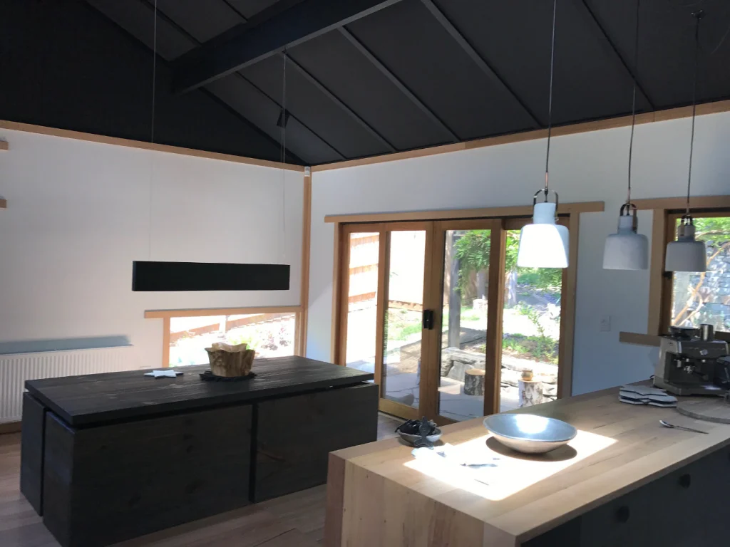 Open kitchen with white walls under a dark raked ceiling